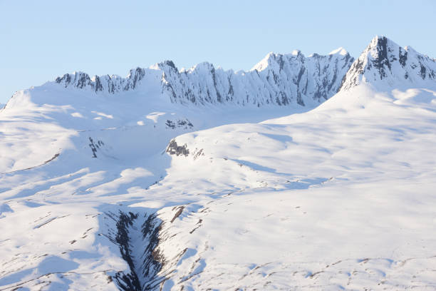 Jagged mountain ridge protruding from a blanket of snow in a glacial icefield between the Chugach Mountains and Wrangell-St. Elias Mountain Range, Alaska.