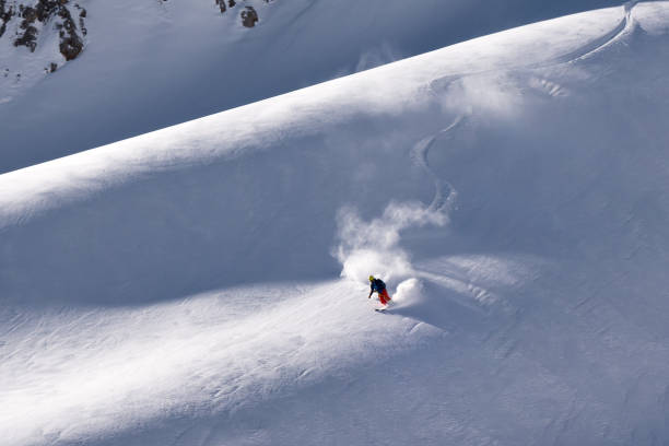 solo lone skidåkare att sätta ner färska första spår på bergsryggen i vinter - heliskiing bildbanksfoton och bilder