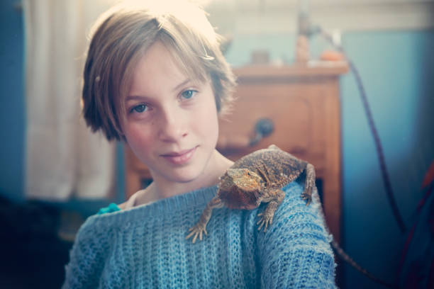 istock Young girl with lizard pet on shoulder in her bedroom. 641596512