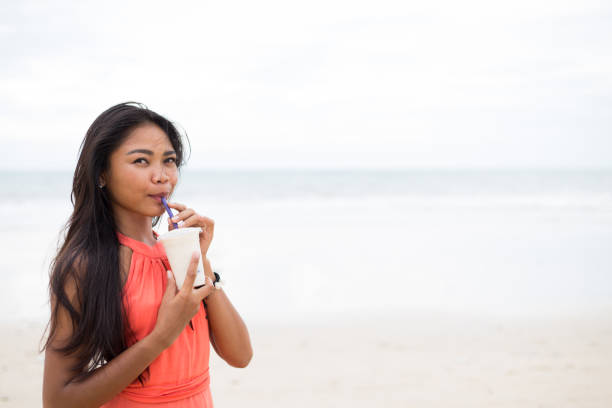 istock Girl drinking a fruit smoothie on the beach 641598728