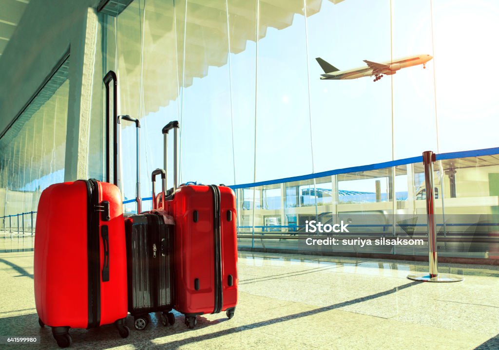 pila de viaje equipaje en la terminal del aeropuerto y avión de pasajeros volando sobre cielo - Foto de stock de Equipaje libre de derechos