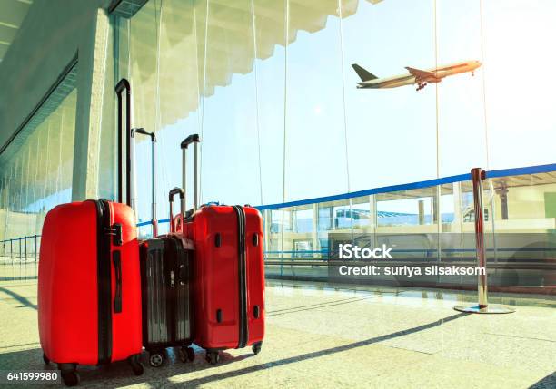 Stack Of Traveling Luggage In Airport Terminal And Passenger Plane Flying Over Sky Stock Photo - Download Image Now