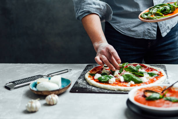 istock Man is spreading basil leaves over pizza 641603228