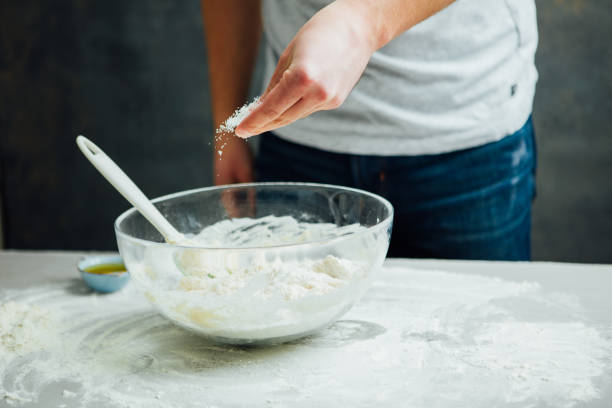 istock Man is sprinkling salt on the dough 641603272