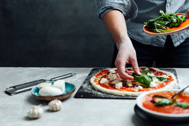 istock Man is spreading basil leaves over pizza 641603548
