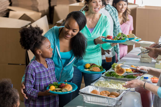 istock Cheerful mom receives meal with daughters in soup kitchen 641609438