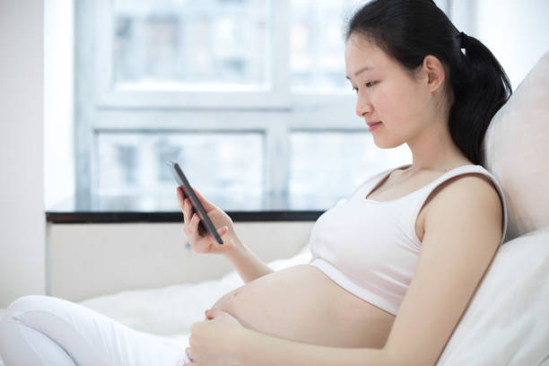 istock pregnant woman with tablet pc computer in bed at home 641610584