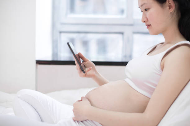 istock pregnant woman with tablet pc computer in bed at home 641610602