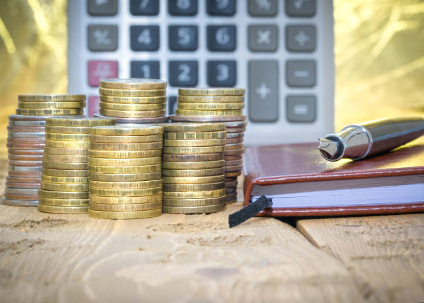 istock Fountain pen,calculator, coins and notebook on a wooden table. 641611010
