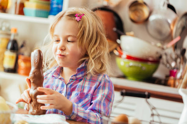 Cute Little Girl Opening Chocolate Easter Bunny Cute little girl opening and eating chocolate Easter bunny chocolate bunny stock pictures, royalty-free photos & images