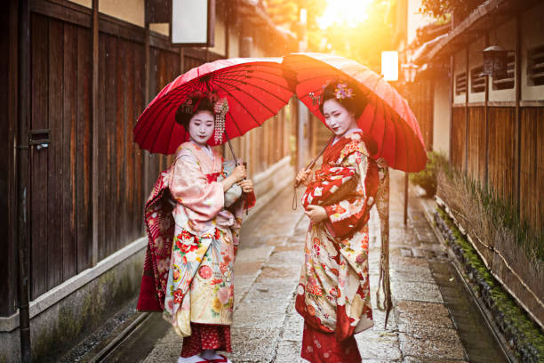 geisha mädchen halten rote regenschirme auf fußweg - parasol umbrella asian ethnicity asian culture stock-fotos und bilder