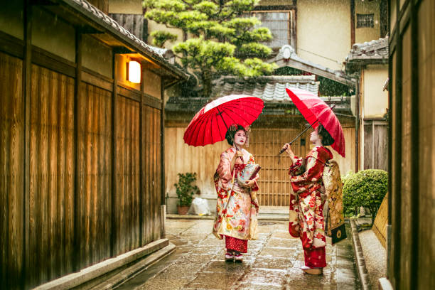 maikos hält rote regenschirme während der regenzeit - parasol umbrella asian ethnicity asian culture stock-fotos und bilder
