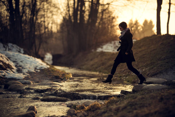 fluxo de mulher em mulher jovem por do sol em um fluxo - stepping stone stone stepping footpath - fotografias e filmes do acervo