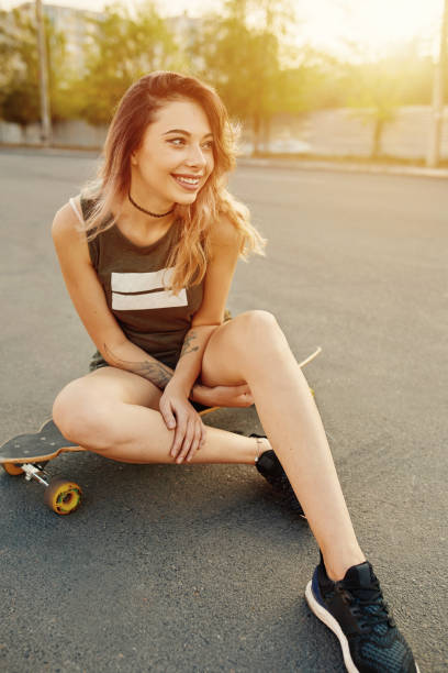istock Beautiful young girl with tattoos sits on longboard 641627744