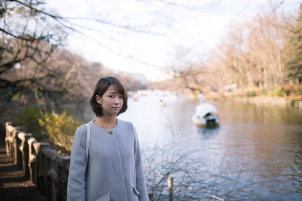 istock Young woman walking along pond in park 641628650