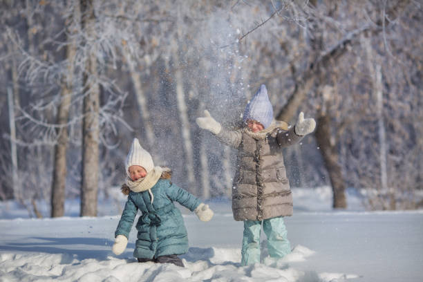 istock Two little sisters play and throw up a snow in winter 641639464