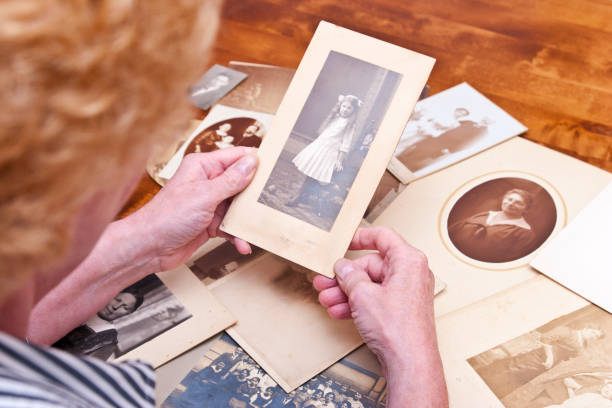 woman looks at old photos of family members - old record imagens e fotografias de stock