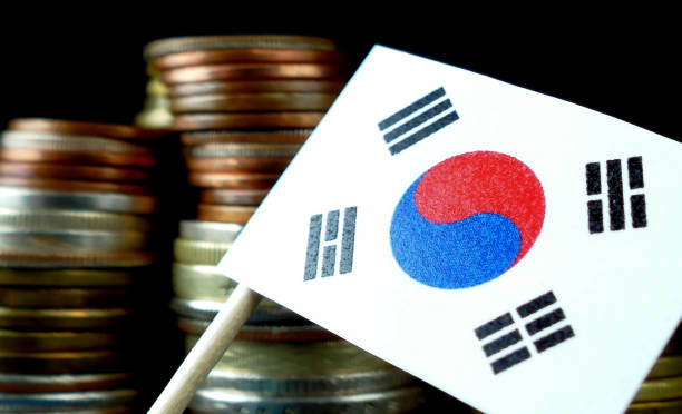 South Korea flag waving with stack of money coins macro stock photo
