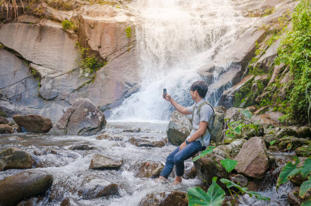 istock Businessman with backpack and laptop and phone at  waterfall  the forest. 641647920