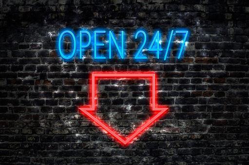 Open 24/7 neon sign on dark brick wall background