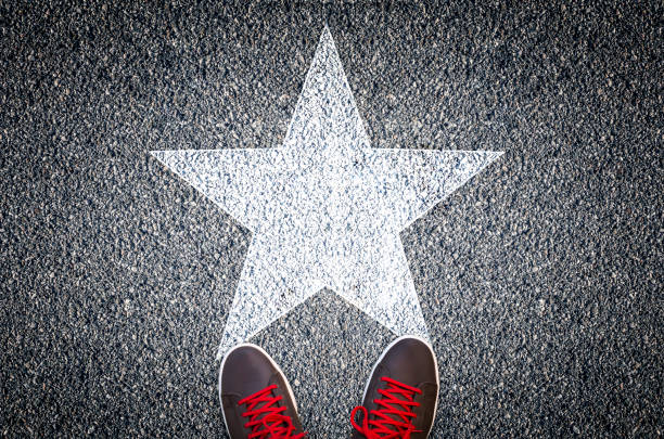 Sneakers on asphalt road with white star stock photo