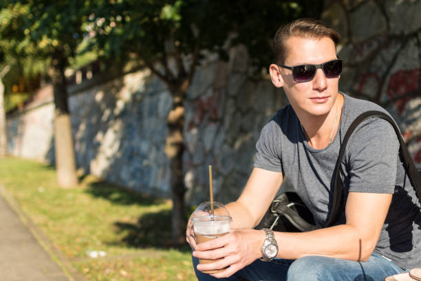 istock Young stylish man with sunglasses having smoothie at the park 641655692