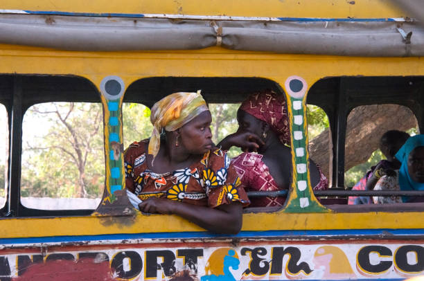 Woman leaning on a Dakar bus Dakar, Senegal - june 02, 2014: Woman dressed in the typical costume of the country, leaning on a transport bus, at a city stop senegal photos stock pictures, royalty-free photos & images