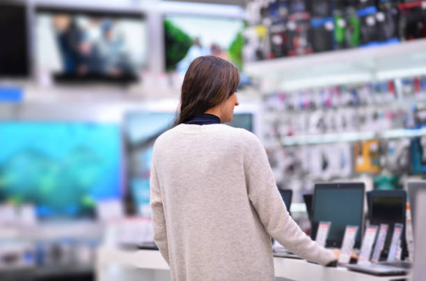 Examining new laptop Woman chooses the laptop in electronics store, shoot with Nikon lens105 mm f/1.4 computer shop stock pictures, royalty-free photos & images