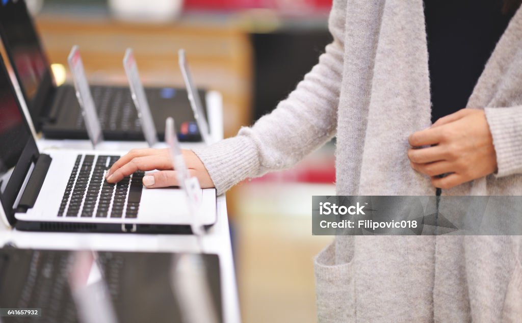 Examining new laptop Woman chooses the laptop in electronics store, shoot with Nikon lens105 mm f/1.4 Computer Store Stock Photo