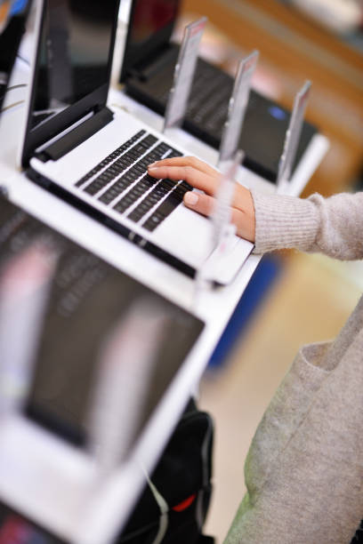 Examining new laptop Woman chooses the laptop in electronics store, shoot with Nikon lens105 mm f/1.4 computer store stock pictures, royalty-free photos & images