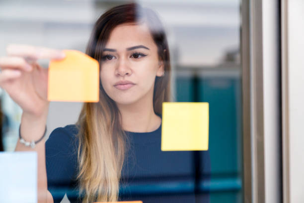 istock Young woman placing adhesive notes on a window 641658256