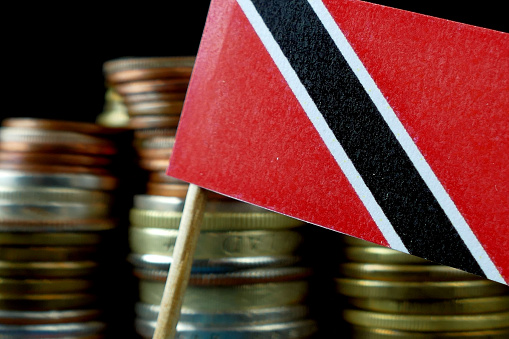 Trinidad and Tobago flag waving with stack of money coins macro