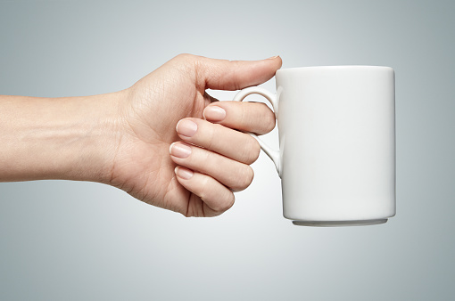 a woman hand holding a coffee mug. isolated. path inside.