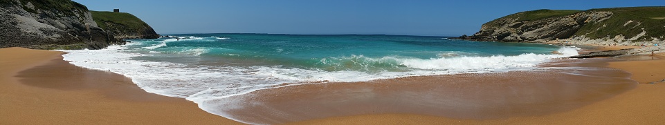 Beach with beautiful waves and blue sky, panoramic. North Spain
