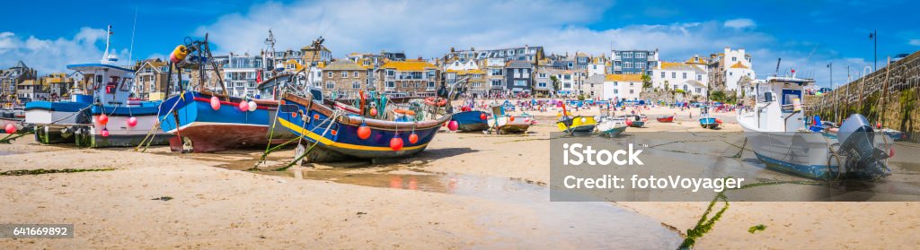 Cornwall St Ives fishing boats and tourists beach harbour panorama Fishing boats moored on the beach in St. Ives harbour, the picturesque seaside resort and fishing village in Cornwall, UK. UK Stock Photo