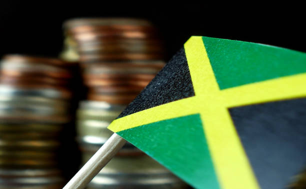 istock Jamaica flag waving with stack of money coins macro 641670626