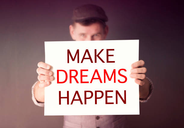 istock man holding sign with words Make Dreams Happen 641671706