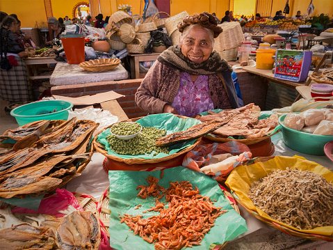 Senior Zapotec woman with traditional braids in her hair selling dried seafood and peas at the Mercado Municipal in Teotitlan del Valle, Oaxaca, Mexico.