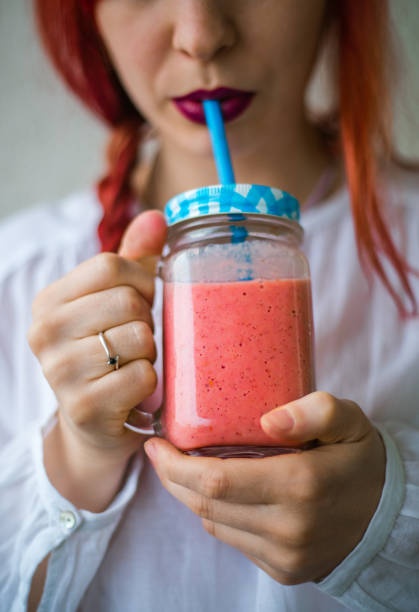 istock Young woman drinking fresh berry smoothie in kitchen 641680604