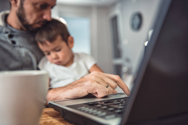 istock Father working on laptop and holding son on his lap 641682292