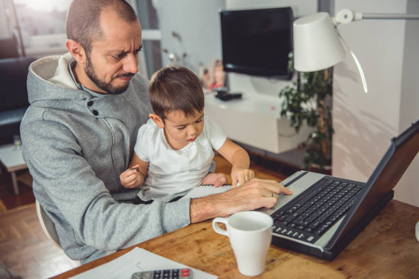 istock Father working on laptop and holding son on his lap 641682296
