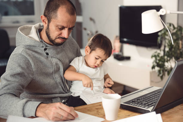 istock Father working at home and holding son on his lap 641682472