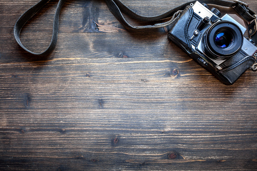 Old retro camera on vintage wooden table background