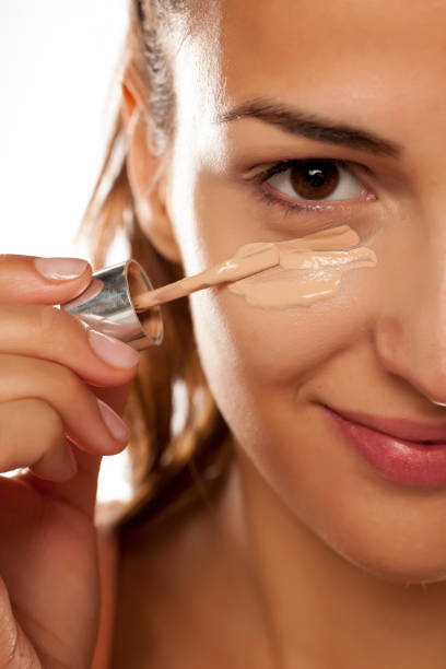 istock young woman applying a liquid foundation on her face 641684800
