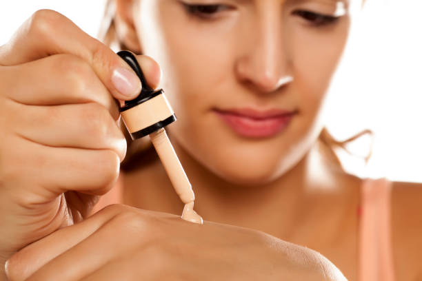 young woman puts a liquid foundation on her palm young woman puts a liquid foundation on her palm liquid foundation face stock pictures, royalty-free photos & images