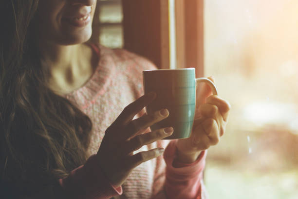 istock woman standing in front of window and drinking coffee 641688178