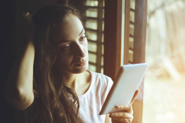 istock young woman using a tablet in the front of the window 641688192