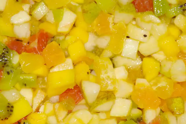 Photo of Cut pieces of fruit to lettuce as a backdrop, pineapple, Kiwi, mango, banana, Orange, Tangerine, grepfrut, pear, Apple