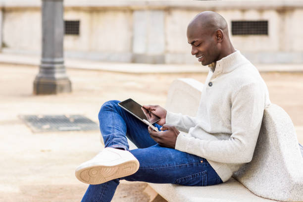 istock Black young man looking at tablet computer and smartphone in urban background. 641692012