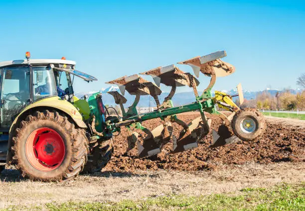 Photo of Tractor plowing a field.Not John Deere but Claas tractor